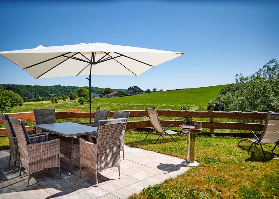 Terrassengarnitur mit 6 Stühlen und Spannschirm für den Sonnenschutz, Grill und weiter Blick in die Felder der Eifel
